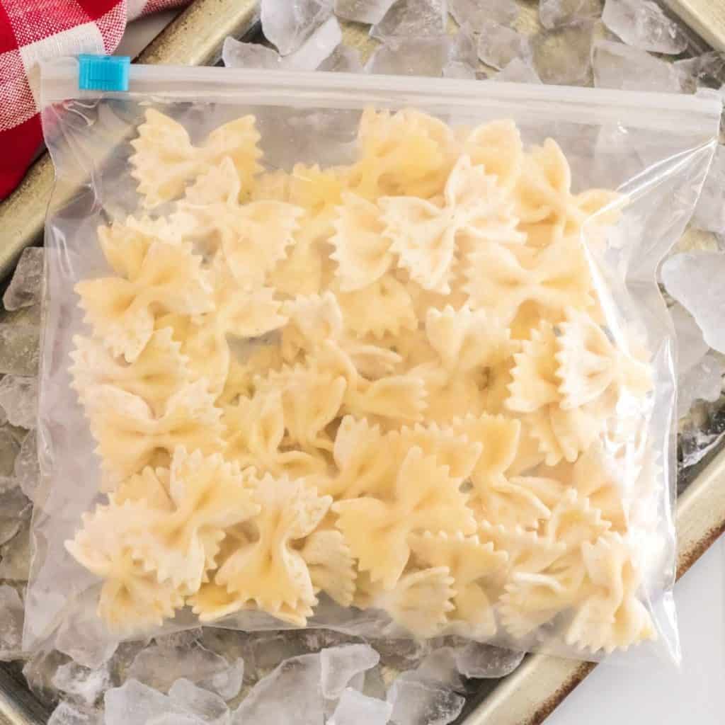 A bag of frozen pasta sits on top of a tray of ice representing how to freeze pasta