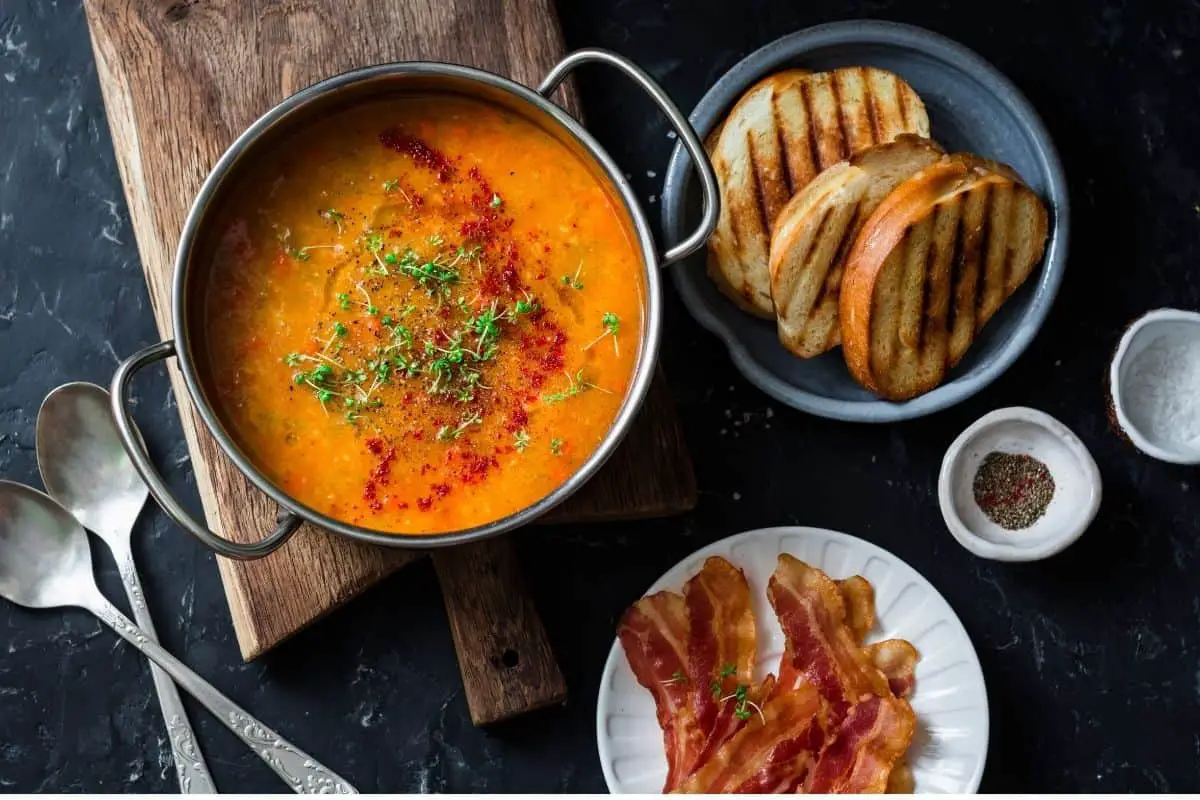 a bowl of tomato soup with toast, and bacon a visual representation of what comfort food is