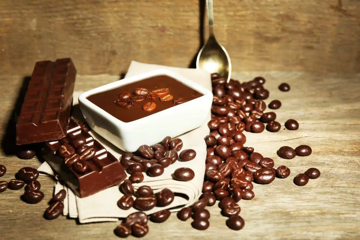 coffee beans floating in chocolate and made into chocolate bars representing the questions how many chocolate covered espresso beans equal a cup of coffee
