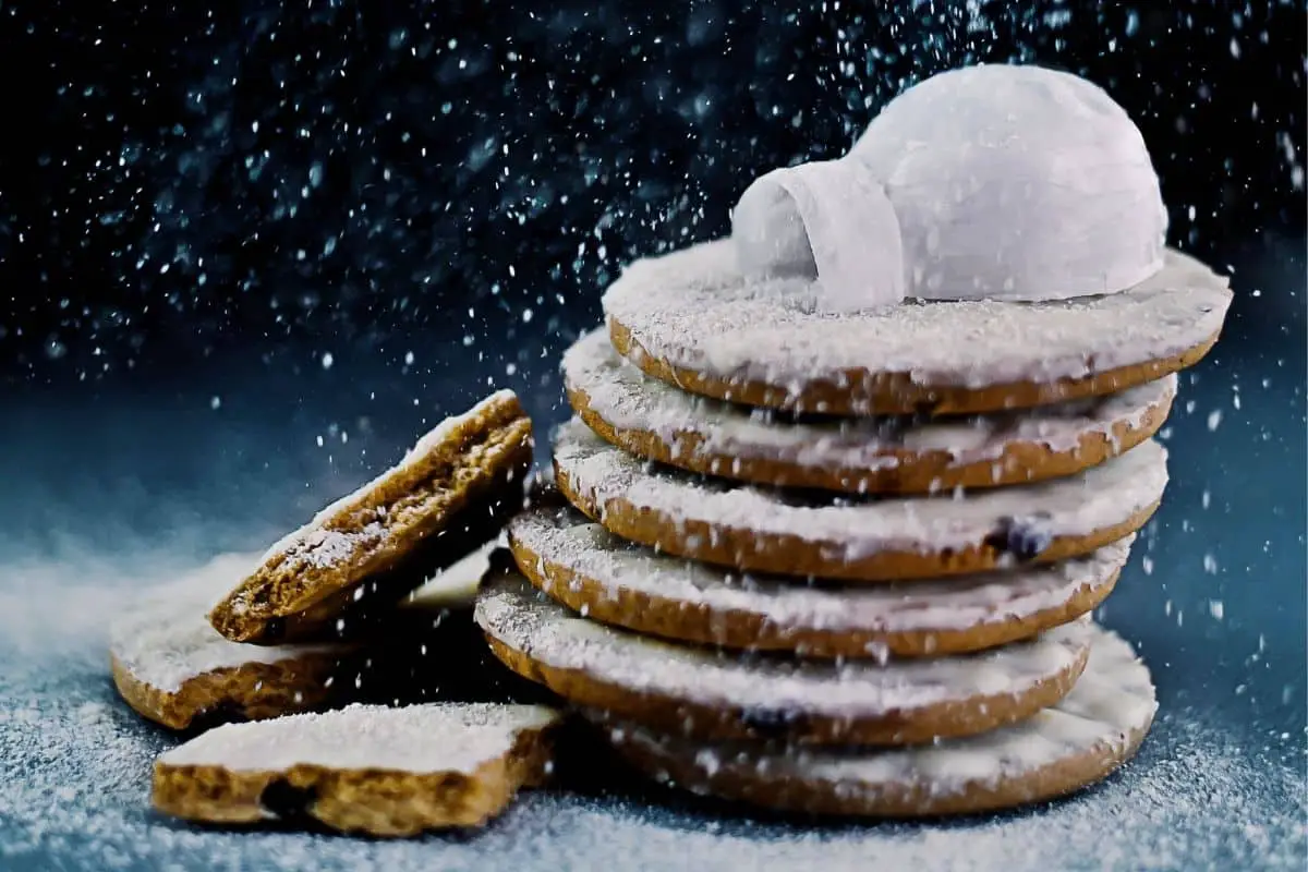 a stack of cookies sprinkled with fresh white powder sugar with an igloo on top representing the question does powder sugar go bad