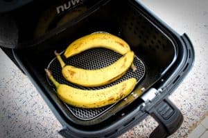 three bananas in an air fryer basket to be getting ready to be ripened for use in baking