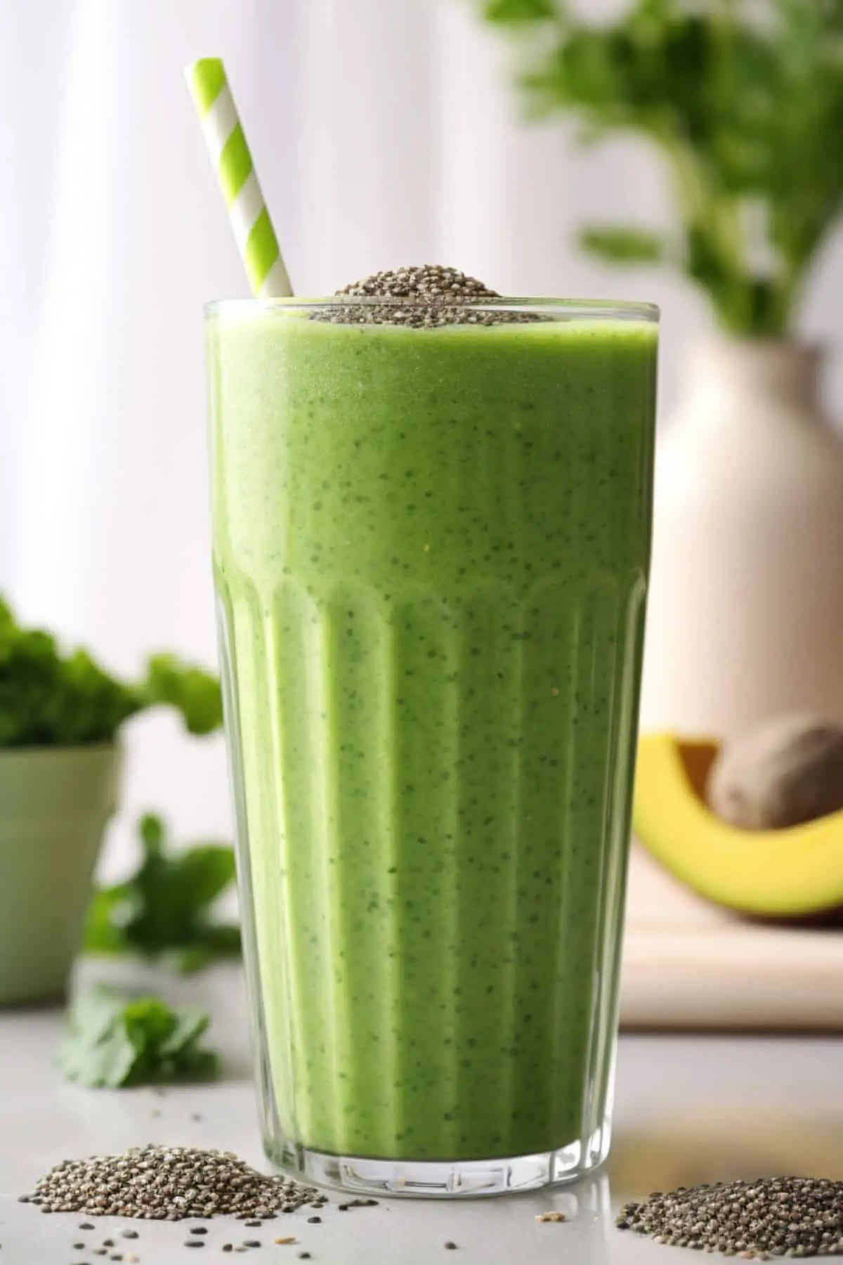A glass full of green chia seed smoothie with chia seeds on top and on each side of the glass
